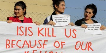 Yazidi refugee women hold a banner as they wait for the arrival of United Nations High Commissioner for Refugees Special Envoy Angelina Jolie at a Syrian and Iraqi refugee camp in the southern Turkish town of Midyat in Mardin province, Turkey, on June 20, 2015. Photo courtesy of REUTERS/Umit Bektas