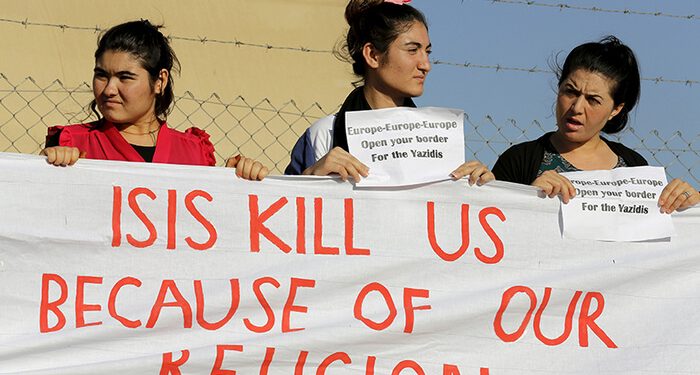 Yazidi refugee women hold a banner as they wait for the arrival of United Nations High Commissioner for Refugees Special Envoy Angelina Jolie at a Syrian and Iraqi refugee camp in the southern Turkish town of Midyat in Mardin province, Turkey, on June 20, 2015. Photo courtesy of REUTERS/Umit Bektas