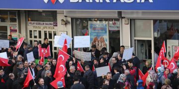 People stage a protest against the seizure of the Islamic Bank Asya, in front of a Bank Asya branch in downtown Ankara on February 4, 2015. Turkey on February 4 defended the seizure of an Islamic bank allied to an arch-foe of President Recep Tayyip Erdogan, the latest crackdown against US-exiled cleric Fethullah Gulen. Bank Asya has suffered major losses since last year after becoming embroiled in a bitter feud between Erdogan and his former ally Gulen, whom the president accuses of seeking to overthrow him. The placard (C) reads "boxes of money were not enough, now it's time to attack Bank Asya".  AFP PHOTO / ADEM ALTAN        (Photo credit should read ADEM ALTAN/AFP/Getty Images)