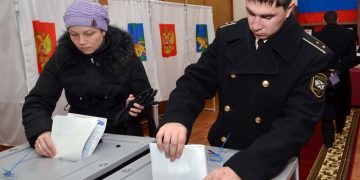 A Russian navy officer and a woman cast their ballots during the parliamentary election in Vladivostok on December 4, 2011. Russians in the Far East began voting in key parliamentary polls expected to hand victory to Vladimir Putin's party amid claims of campaign fraud and unprecedented intimidation of observers. AFP PHOTO / GENNADY SHISHKIN