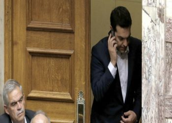 Greece's Prime Minister Alexis Tsipras speaks from his mobile phone during emergency Parliament session for the governments proposed referendum in Athens, Saturday, June 27, 2015. Greece's place in the euro currency bloc looked increasingly shaky on Saturday, when eurozone countries rejected a monthlong extension to its bailout program and the prime minister called for a risky popular vote on the country's financial future. (AP Photo/Petros Karadjias)