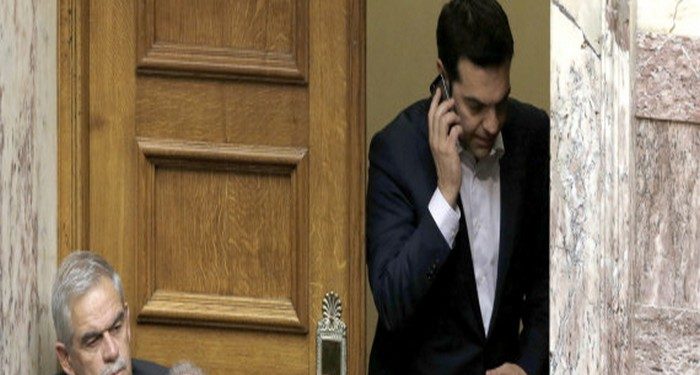 Greece's Prime Minister Alexis Tsipras speaks from his mobile phone during emergency Parliament session for the governments proposed referendum in Athens, Saturday, June 27, 2015. Greece's place in the euro currency bloc looked increasingly shaky on Saturday, when eurozone countries rejected a monthlong extension to its bailout program and the prime minister called for a risky popular vote on the country's financial future. (AP Photo/Petros Karadjias)