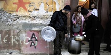 Activists of a  soup kitchen deliver food to an immigrant family in a poor neighborhood in Athens, on February 6, 2012. Greece today began constructing a fence on its border with Turkey to keep out thousands of undocumented migrants and refugees seeking to cross into Europe, the country's police minister said.  AFP PHOTO / LOUISA GOULIAMAKI