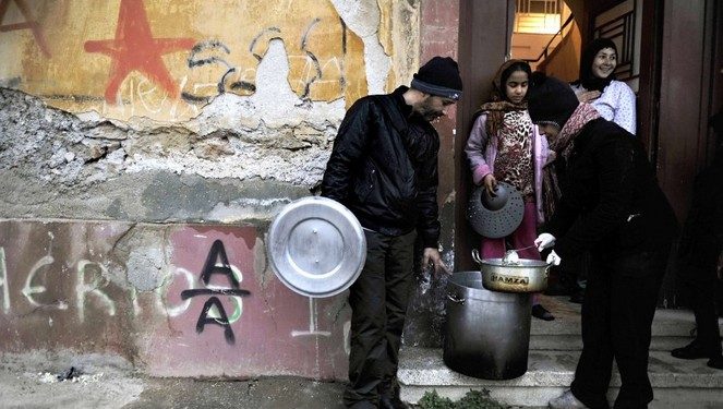 Activists of a  soup kitchen deliver food to an immigrant family in a poor neighborhood in Athens, on February 6, 2012. Greece today began constructing a fence on its border with Turkey to keep out thousands of undocumented migrants and refugees seeking to cross into Europe, the country's police minister said.  AFP PHOTO / LOUISA GOULIAMAKI