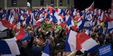 epa05647742 People wave French flags as candidate for the right-wing Les Republicains (LR) party primaries ahead of the 2017 presidential election and former French Prime Minister, Francois Fillon delivers a speech during the nation anthem during a political rally of the second round of the rightwing presidential primary, in Paris, France, 25 November 2016. Francois Fillon took a commanding lead in the two-round primary that is widely expected to decide the country's next leader. The second round will be held on 27 November 2016.  EPA/IAN LANGSDON