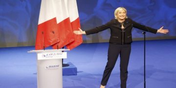 Far-right leader presidential candidate Marine Le Pen acknowledges applauses as she arrives as to a conference in Lyon, France, Sunday, Feb. 5, 2017. Marine Le Pen, the far-right presidential candidate, unveiled her platform Saturday at the start of a weekend conference, envisioning a thriving nation "made in France. (AP Photo/Michel Euler)