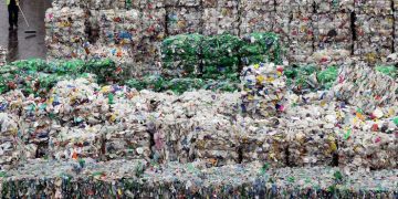 LONDON - MARCH 25:  An employee of the 'Closed Loop Recycling' plant walks past stacks of plastic bottles at their plant in Dagenham on March 25, 2010 in London, United Kingdom. The state of the art plant is the first in the UK to produce food grade recycled plastic from bottle waste. Over 35,00 tonnes of plastic bottles are recycled at the plant annually, representing almost 20% of the plastic bottles currently collected for recycling in the UK, and saving approximately 52,500 tonnes of carbon dioxide per year.  (Photo by Dan Kitwood/Getty Images)