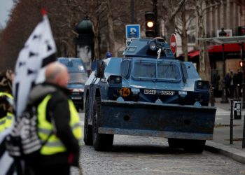 Protesters wearing yellow vests walk near armoured gendarmerie vehicles as they arrive to attend a demonstration by the "yellow vests" movement in Paris, France, December 8, 2018. REUTERS/Benoit Tessier