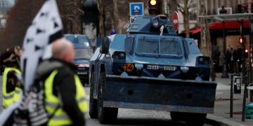 Protesters wearing yellow vests walk near armoured gendarmerie vehicles as they arrive to attend a demonstration by the "yellow vests" movement in Paris, France, December 8, 2018. REUTERS/Benoit Tessier