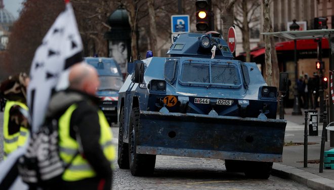 Protesters wearing yellow vests walk near armoured gendarmerie vehicles as they arrive to attend a demonstration by the "yellow vests" movement in Paris, France, December 8, 2018. REUTERS/Benoit Tessier