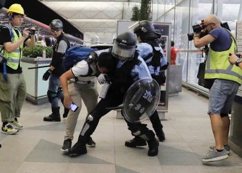 Policemen in riot gears arrest a protester during a demonstration at the Airport in Hong Kong, Tuesday, Aug. 13, 2019. Chaos has broken out at Hong Kong's airport as riot police moved into the terminal to confront protesters who shut down operations at the busy transport hub for two straight days. (AP Photo/Kin Cheung)