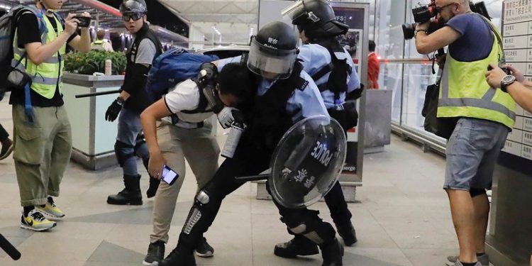 Policemen in riot gears arrest a protester during a demonstration at the Airport in Hong Kong, Tuesday, Aug. 13, 2019. Chaos has broken out at Hong Kong's airport as riot police moved into the terminal to confront protesters who shut down operations at the busy transport hub for two straight days. (AP Photo/Kin Cheung)