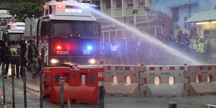 epaselect epa07792203 An anti-riot police vehicle equipped with a water cannon clears the road from a barricade set up by protesters during an anti-government rally in Kwai Fung and Tsuen Wan, Hong Kong, China, 25 August 2019. The protests were triggered last June by an extradition bill to China, now suspended, and evolved into a wider anti-government movement with no end in sight.  EPA/JEROME FAVRE