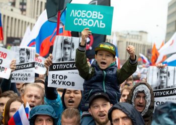 People with posters show portraits of detained protesters and a boy with a poster reads Lyubov Sobol react during a protest in Moscow, Russia, Saturday, Aug. 10, 2019. Tens of thousands of people rallied in central Moscow for the third consecutive weekend to protest the exclusion of opposition and independent candidates from the Russian capital's city council ballot. (AP Photo/Alexander Zemlianichenko)