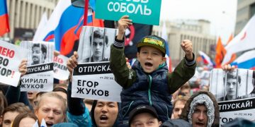 People with posters show portraits of detained protesters and a boy with a poster reads Lyubov Sobol react during a protest in Moscow, Russia, Saturday, Aug. 10, 2019. Tens of thousands of people rallied in central Moscow for the third consecutive weekend to protest the exclusion of opposition and independent candidates from the Russian capital's city council ballot. (AP Photo/Alexander Zemlianichenko)