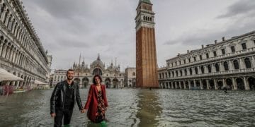 VENICE, ITALY - OCTOBER 29: A couple of tourists walk in "Piazza San Marco" on October 29, 2018 in Venice, Italy. Due to the exceptional level of the "acqua alta" or "High Tide" that reached 156 cm today, Venetian schools and hospitals were closed by the authorities, and citizens were advised against leaving their homes . (Photo by Stefano Mazzola/Awakening/Getty Images)