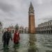 VENICE, ITALY - OCTOBER 29: A couple of tourists walk in "Piazza San Marco" on October 29, 2018 in Venice, Italy. Due to the exceptional level of the "acqua alta" or "High Tide" that reached 156 cm today, Venetian schools and hospitals were closed by the authorities, and citizens were advised against leaving their homes . (Photo by Stefano Mazzola/Awakening/Getty Images)