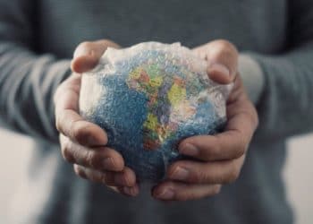 closeup of a young caucasian man with a world globe wrapped in bubble wrap in his hands