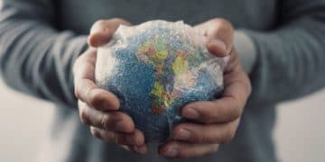 closeup of a young caucasian man with a world globe wrapped in bubble wrap in his hands