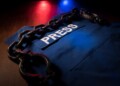 Freedom of the press and journalism concept. Blue journalist (press) vest in dark with backlight and fog. Shackles on vest. Selective focus