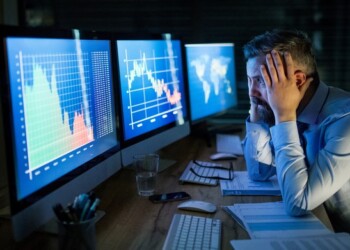 Frustrated and worried businessman with computer sitting at desk, working late. Financial crisis concept.