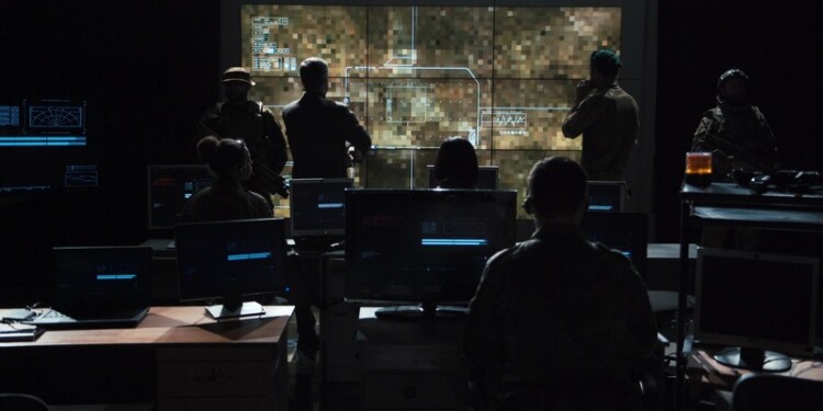 Group of soldiers or spies in dark room with large monitors and advanced satellite communication technology launching a missle. Includes flashing yellow light.