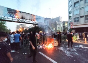 TOPSHOT - A picture obtained by AFP outside Iran on September 21, 2022, shows Iranian demonstrators burning a rubbish bin in the capital Tehran during a protest for Mahsa Amini, days after she died in police custody. Protests spread to 15 cities across Iran overnight over the death of the young woman Mahsa Amini after her arrest by the country's morality police, state media reported today.In the fifth night of street rallies, police used tear gas and made arrests to disperse crowds of up to 1,000 people, the official IRNA news agency said.
 (Photo by AFP)