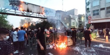 TOPSHOT - A picture obtained by AFP outside Iran on September 21, 2022, shows Iranian demonstrators burning a rubbish bin in the capital Tehran during a protest for Mahsa Amini, days after she died in police custody. Protests spread to 15 cities across Iran overnight over the death of the young woman Mahsa Amini after her arrest by the country's morality police, state media reported today.In the fifth night of street rallies, police used tear gas and made arrests to disperse crowds of up to 1,000 people, the official IRNA news agency said.
 (Photo by AFP)