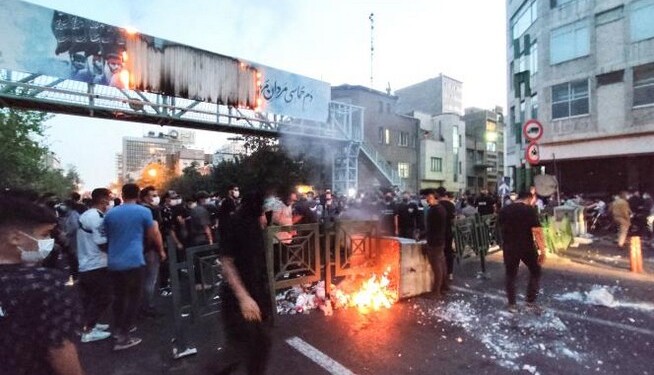 TOPSHOT - A picture obtained by AFP outside Iran on September 21, 2022, shows Iranian demonstrators burning a rubbish bin in the capital Tehran during a protest for Mahsa Amini, days after she died in police custody. Protests spread to 15 cities across Iran overnight over the death of the young woman Mahsa Amini after her arrest by the country's morality police, state media reported today.In the fifth night of street rallies, police used tear gas and made arrests to disperse crowds of up to 1,000 people, the official IRNA news agency said.
 (Photo by AFP)