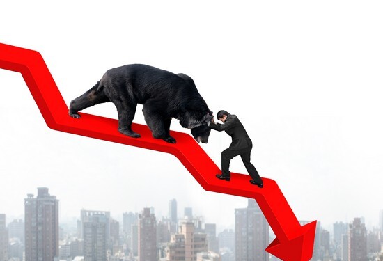 Businessman against black bear on red arrow downward trend line with sky cityscape background. Fight back bearish market concept.