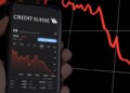 New York, US, March 2023: hand holding a phone with the performance of Credit Suisse on stock market. In March 2023, Credit Suisse experienced a sharp drop in its stock price. Illustrative editorial