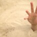 Hand sinking in quicksand, trying to get out, tips to survive in desert, buried