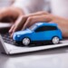 Close-up Of A Small Blue Car On Laptop Keypad