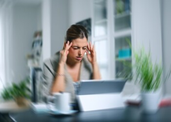 Sick dizzy young woman suffering headache while working on her laptop at home.