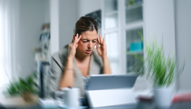 Sick dizzy young woman suffering headache while working on her laptop at home.