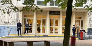 Police officers stand guard outside the high school where a man stabbed a teacher, Saturday Oct.14, 2023 in Arras, northern France. A man of Chechen origin who was under surveillance by French security services over suspected Islamic radicalization stabbed a teacher to death at his former high school and wounded three other people Friday in Arras. (AP Photo/Jeffrey Schaeffer)