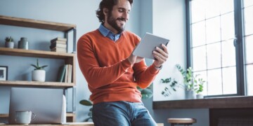 Businessman leaning on the table and working on digital tablet.