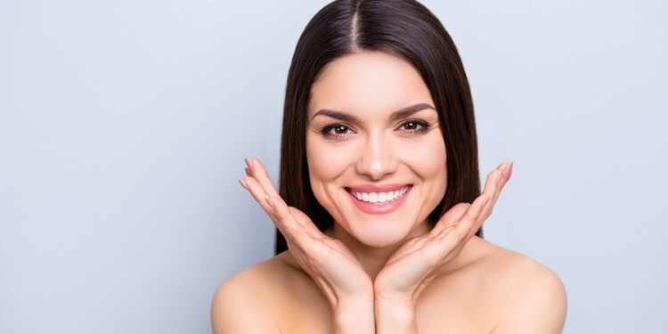 Portrait of gorgeous toothy woman presenting perfect smooth soft idyllic face skin isolated on grey background. Detox botox collagen vitamins minerals wellness wellbeing enhancement concept