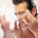 Middle-aged man in bathroom applying facial lotion