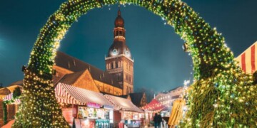 Riga, Latvia. Traditional Christmas Market On Dome Square With Riga Dome Cathedral. Famous Landmark In Winter Evening Night In Festive Illuminations Lighting