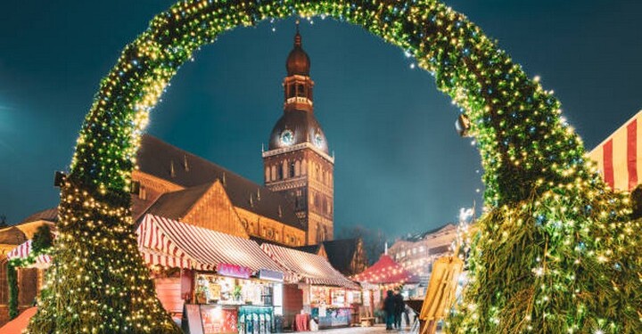 Riga, Latvia. Traditional Christmas Market On Dome Square With Riga Dome Cathedral. Famous Landmark In Winter Evening Night In Festive Illuminations Lighting