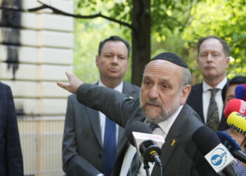 Poland's chief rabbi Michael Schudrich points to the Nożyk Synagogue in Warsaw, Poland, on Wednesday, May 1, 2024. The synagogue was damaged in a attack with Molotov cocktails overnight. (AP Photo/Czarek Sokolowski)