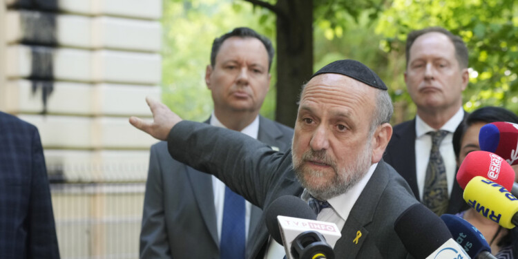 Poland's chief rabbi Michael Schudrich points to the Nożyk Synagogue in Warsaw, Poland, on Wednesday, May 1, 2024. The synagogue was damaged in a attack with Molotov cocktails overnight. (AP Photo/Czarek Sokolowski)