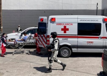 A security officer walks past as the Red Cross loads a patient, injured in a migrant detention center fire, into an ambulance, Tuesday, March 28, 2023, at a hospital in Cuidad Juarez, Mexico. According to Mexican President Andres Manuel Lopez Obrador, migrants fearing deportation set mattresses ablaze at the center, starting the fire that killed at least 40 migrants. (AP Photo/Morgan Lee)