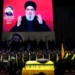 Hezbollah fighters stand behind the coffin of their top commander Fouad Shukur, who was killed by an Israeli airstrike on Tuesday, July 30, as Hezbollah leader Sayyed Hassan Nasrallah speaks through a screen during Shukur's funeral in a southern suburb of Beirut, Lebanon, Aug. 1, 2024. (AP Photo/Hussein Malla)