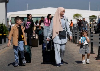 Turkish citizens carry their belongings, as they arrive at a gathering point to board a Turkish navy vessel to be evacuated to Turkey, in Beirut, Lebanon, Wednesday, Oct. 9, 2024. (AP Photo/Hussein Malla)