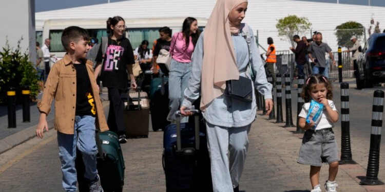 Turkish citizens carry their belongings, as they arrive at a gathering point to board a Turkish navy vessel to be evacuated to Turkey, in Beirut, Lebanon, Wednesday, Oct. 9, 2024. (AP Photo/Hussein Malla)