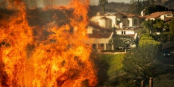 Flames rise as the Palisades Fire advances on homes in the Pacific Palisades neighborhood of Los Angeles, Tuesday, Jan. 7, 2025. (AP Photo/Ethan Swope)