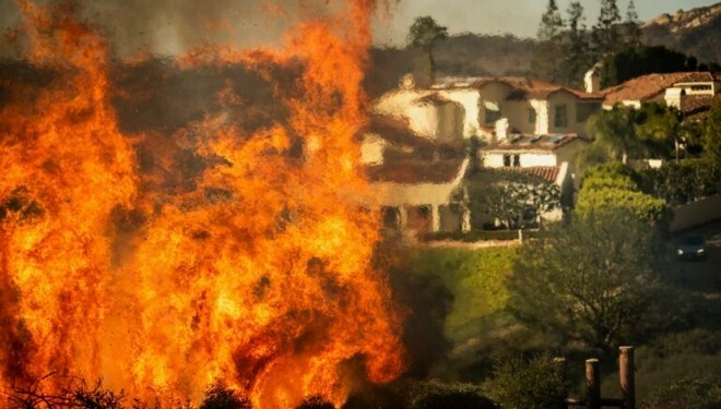 Flames rise as the Palisades Fire advances on homes in the Pacific Palisades neighborhood of Los Angeles, Tuesday, Jan. 7, 2025. (AP Photo/Ethan Swope)