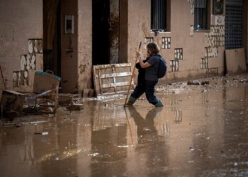 A woman walks through the mud as she tries to arrive at her home on a still flooded street in Masanasa, Valencia, Spain, Thursday, Nov. 7, 2024. (AP Photo/Emilio Morenatti)